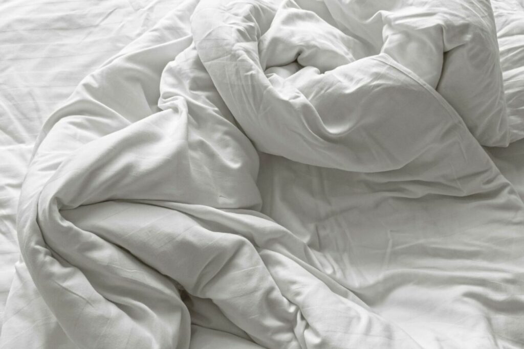 Pressing Nîmes : comment bien choisir ? Couette froissée dans un lit avant nettoyage en blanchisserie